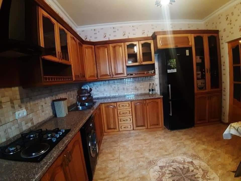 a kitchen with wooden cabinets and a black refrigerator at Green garden Կանաչ այգի in Ijevan