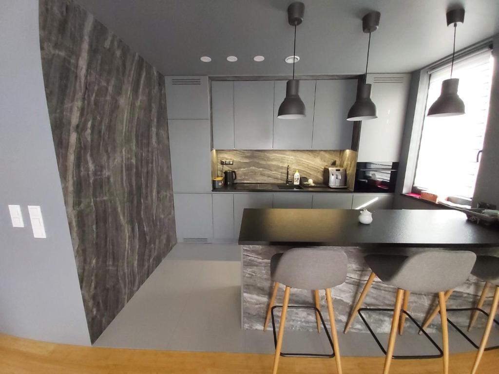 eine Küche mit einer schwarzen Theke und 2 Stühlen in der Unterkunft Wizjonerów Luxury Apartment & Garage in Krakau