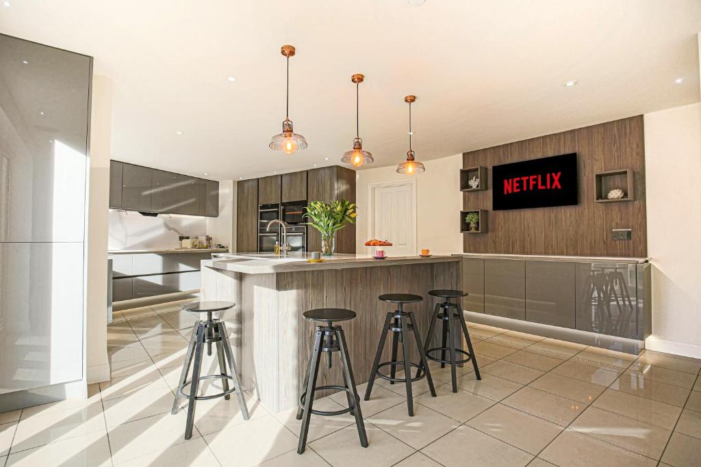 a kitchen with a counter and stools in it at Luxury 5 Bedroom House Bicester Village Central Location in Bicester