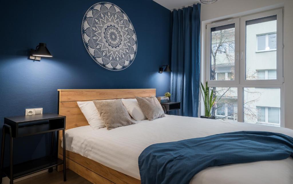 une chambre avec un lit aux murs bleus et une fenêtre dans l'établissement Apartament LindEGO, à Toruń