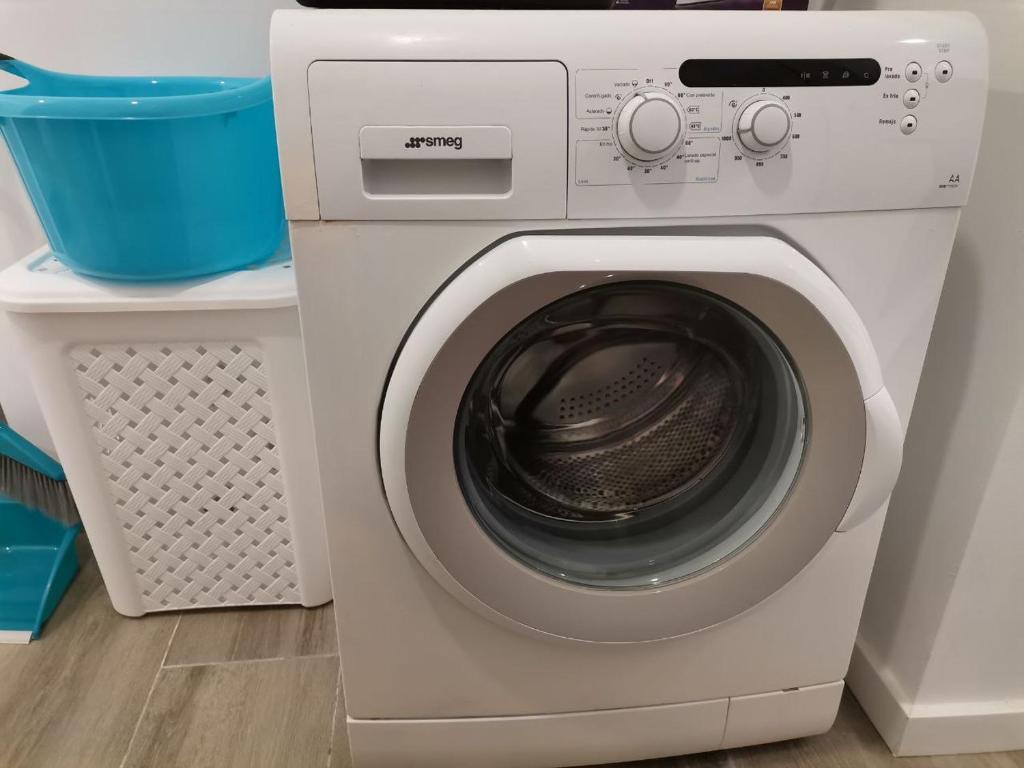 a white washing machine sitting next to a laundry basket at Canyelles BBQ Apartment in Lloret de Mar