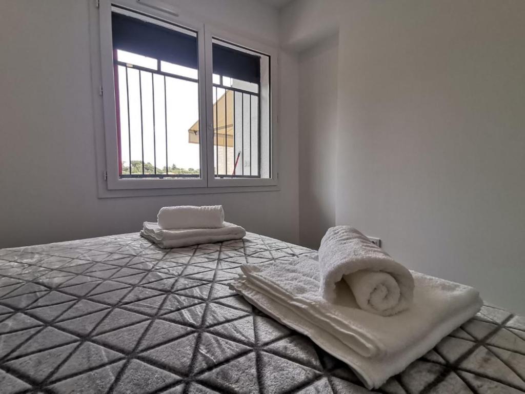 a white room with a bed with towels on it at Canyelles BBQ Apartment in Lloret de Mar