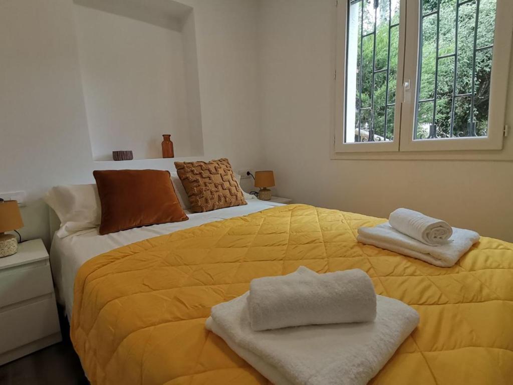 a bedroom with a large yellow bed with towels on it at Canyelles BBQ Apartment in Lloret de Mar