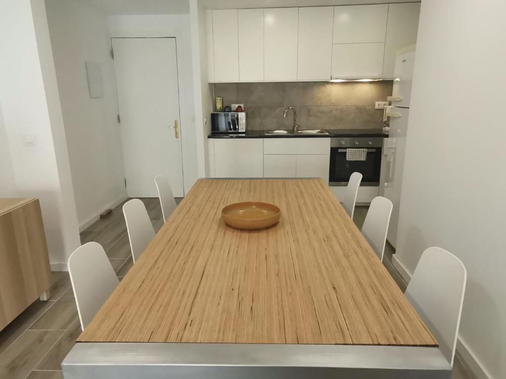 a wooden table in a kitchen with white cabinets at Canyelles BBQ Apartment in Lloret de Mar