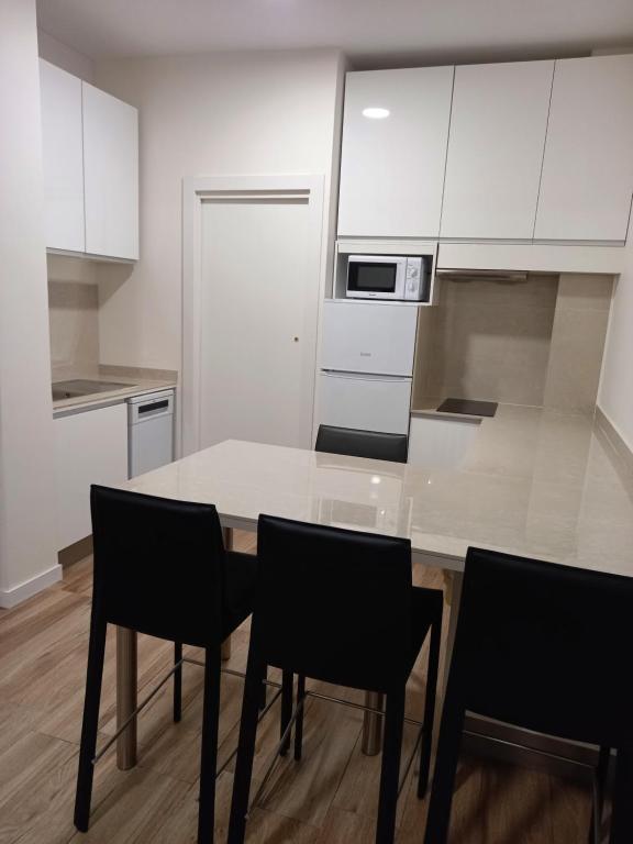 a kitchen with a table and chairs and a microwave at Cervante Apartment in Alcalá de Henares