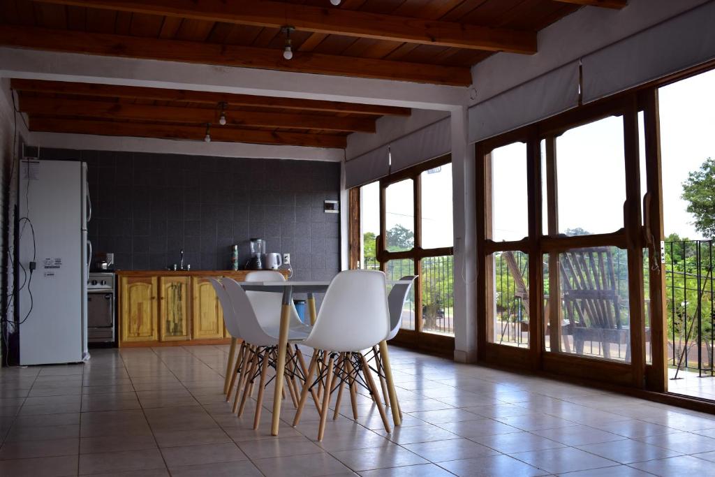 uma cozinha com cadeiras brancas, uma mesa e janelas em Casa Cumandai em San Javier