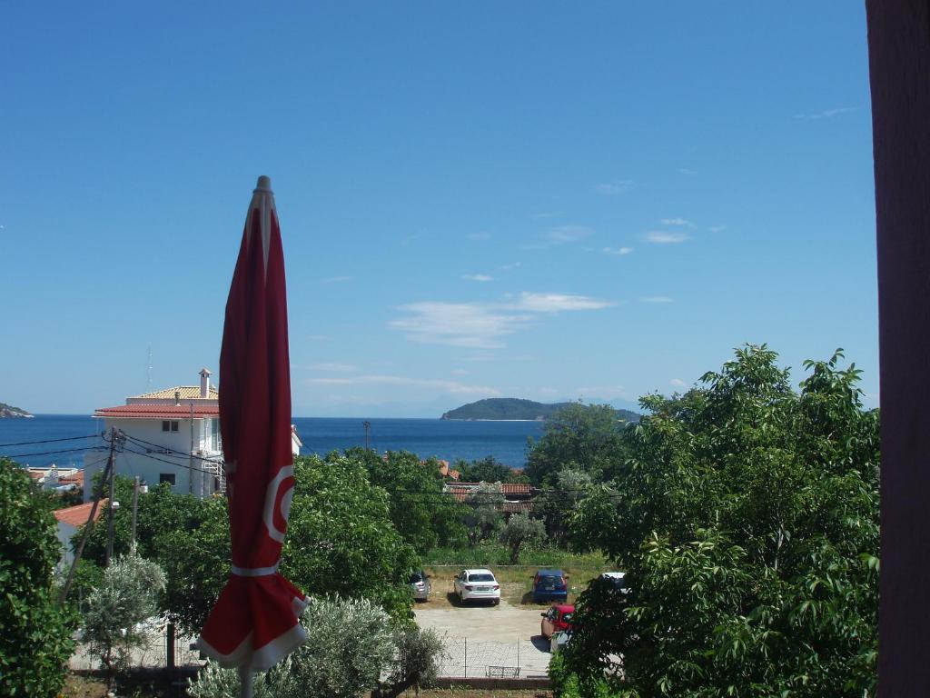 a red umbrella with a view of a parking lot at SKIATHOS STUDIOS in Skiathos Town