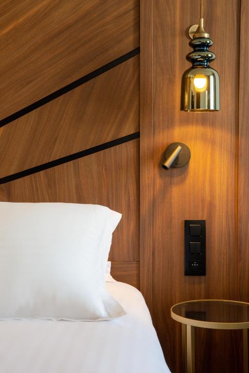a bedroom with a bed and a light and a lamp at Hôtel Apollinaire Nice in Nice