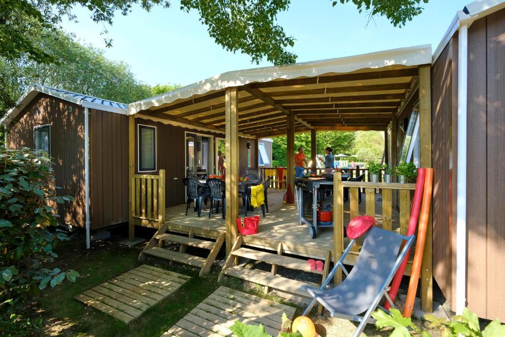 a house with a deck with a table and chairs at Camping Capfun La Bretèche in Les Épesses