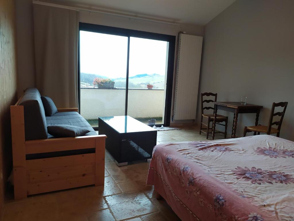 ein Schlafzimmer mit einem Bett, einem Sofa und einem Fenster in der Unterkunft Limone Vallée in Montrigaud