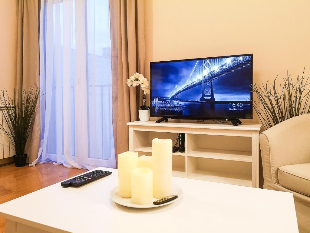 una sala de estar con TV y velas sobre una mesa en FilinHome Papa Suite 3, en Novi Sad