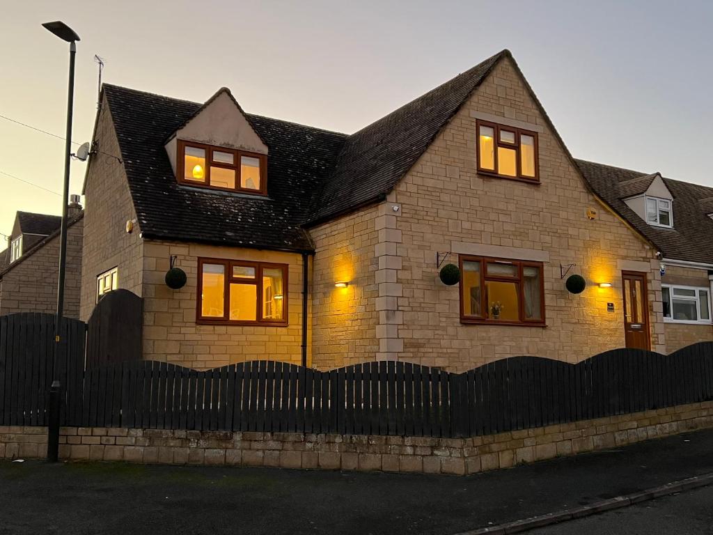 a brick house with two windows and a fence at Luxurious 4 bedroom home in the heart of the Cotswolds with Hot Tub! in Stow on the Wold