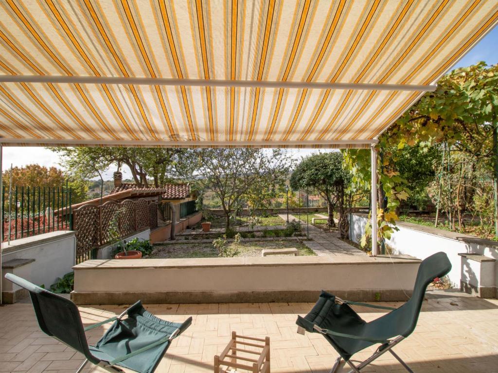 eine Terrasse mit Stühlen und einem großen Sonnenschirm in der Unterkunft Apartment Kiwi e L'uva by Interhome in Fabrica di Roma