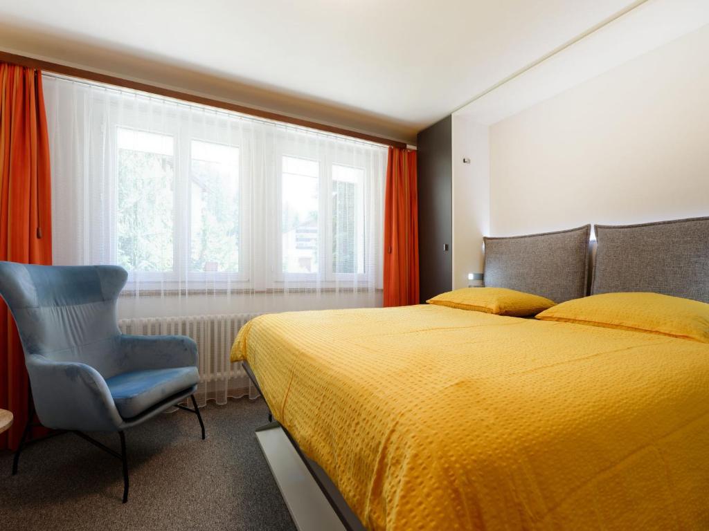 - une chambre avec un lit jaune et une chaise bleue dans l'établissement Apartment Hubertus-1 by Interhome, à Zermatt