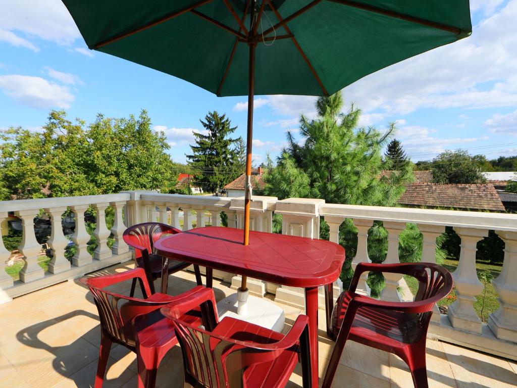 een rode tafel en stoelen met een paraplu op een terras bij Holiday Home Elisabeta Grande by Interhome in Balatonőszöd
