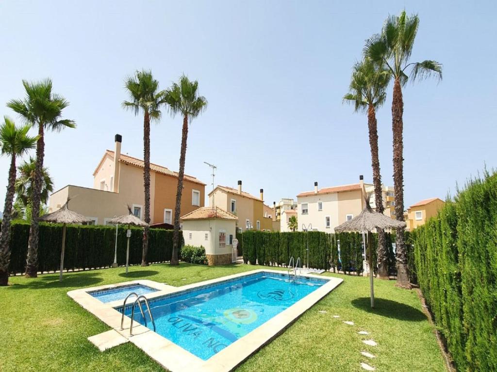 einen Pool in einem Garten mit Palmen in der Unterkunft Holiday Home Malibu Beach by Interhome in Oliva