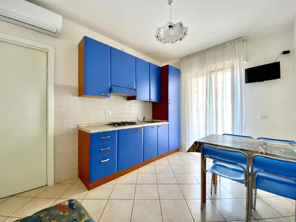 cocina azul con mesa y armarios azules en Rialto, en Lignano Sabbiadoro
