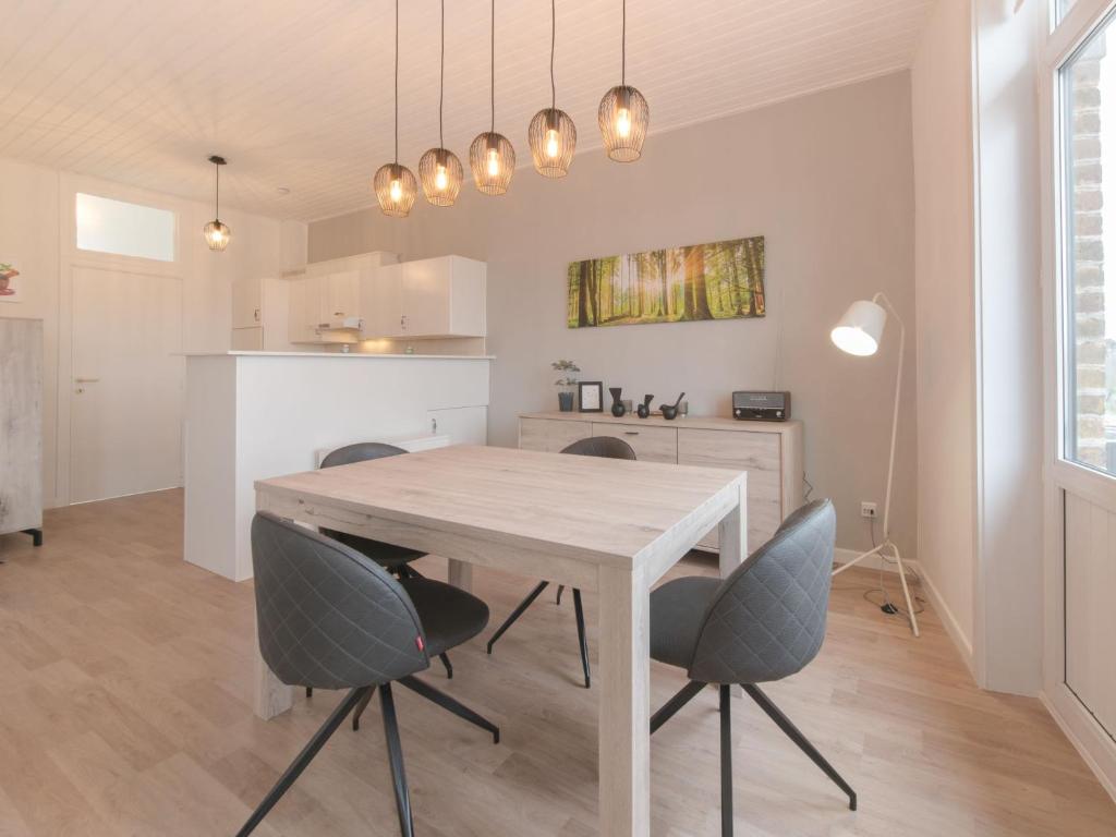 eine Küche und ein Esszimmer mit einem Holztisch und Stühlen in der Unterkunft Apartment Carnac Station by Interhome in De Haan