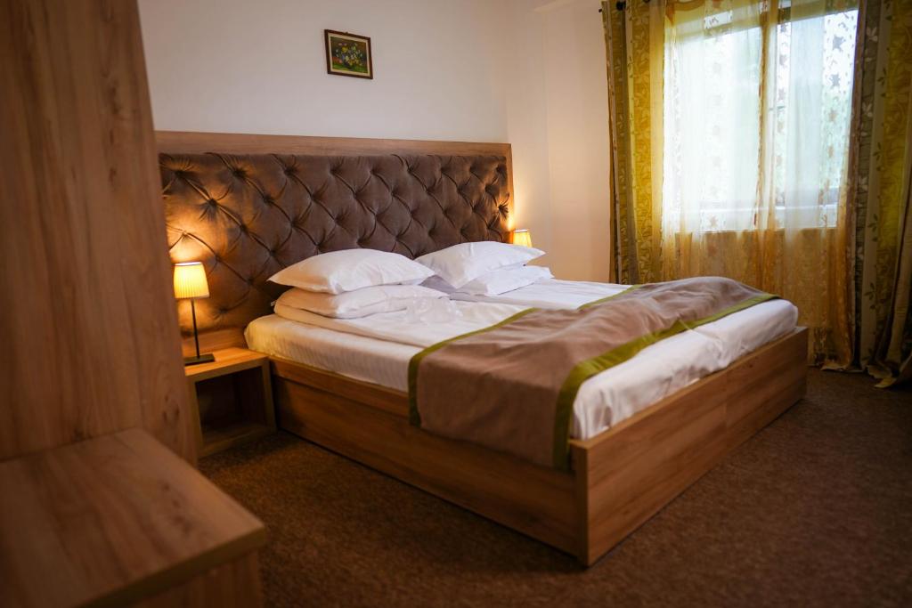 um quarto com uma cama grande, uma cabeceira e uma janela em Pension Casa cu Tei em Sarata-Monteoru