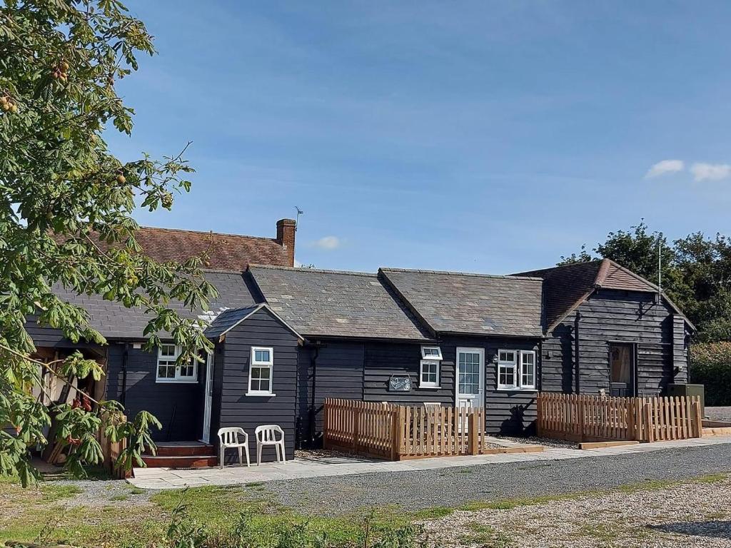 uma casa preta com duas cadeiras à frente em Great Sampford B&B Sorrells farm em Hempstead