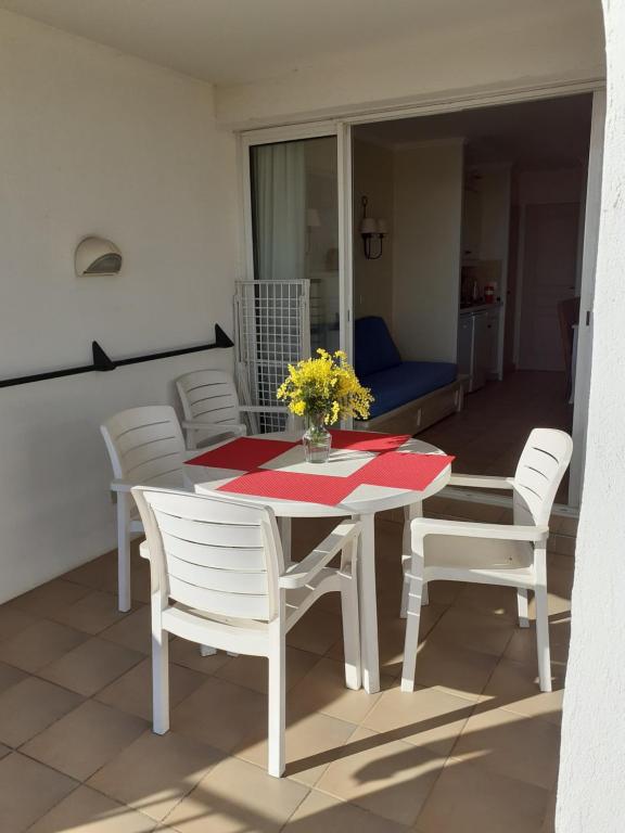 a dining room table with white chairs and a vase of flowers at les Restanques Du Golf de Saint Tropez, 83310 Grimaud, France Appartement in Grimaud