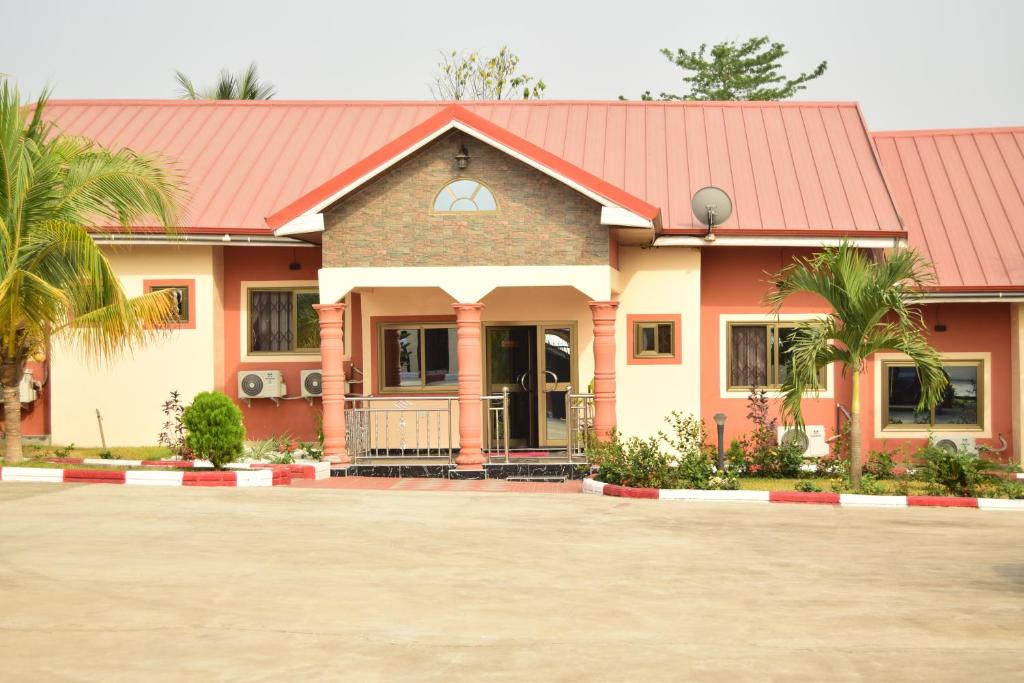 una casa con techo rojo y palmeras en Absor Royal Hotel en Koforidua