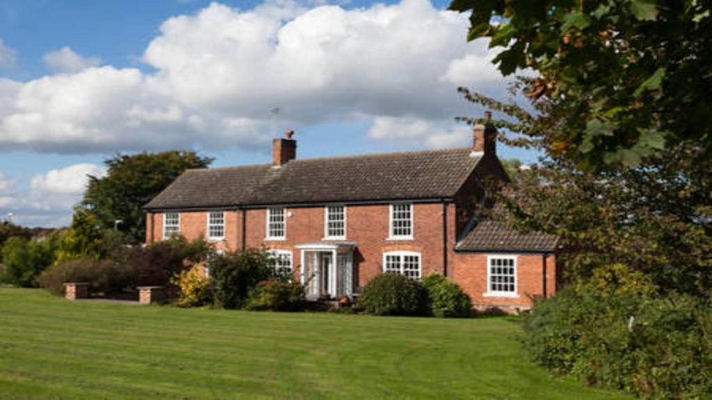 a large red brick house on a green field at Clumber Lane End Farm in Worksop