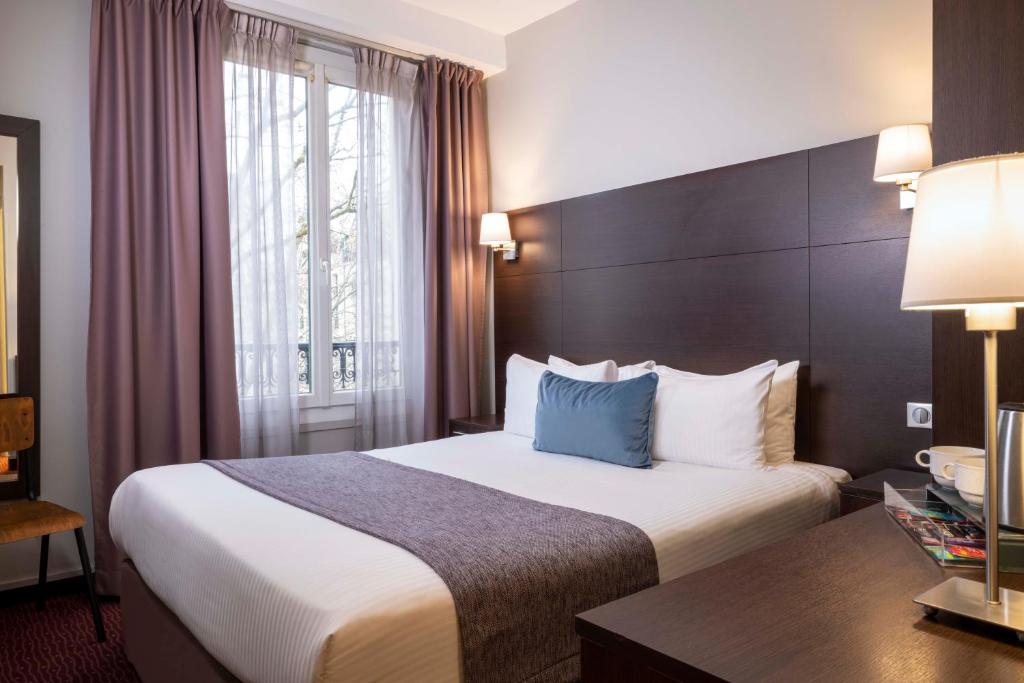 パリにあるHôtel L'Interludeのベッドとデスクが備わるホテルルームです。