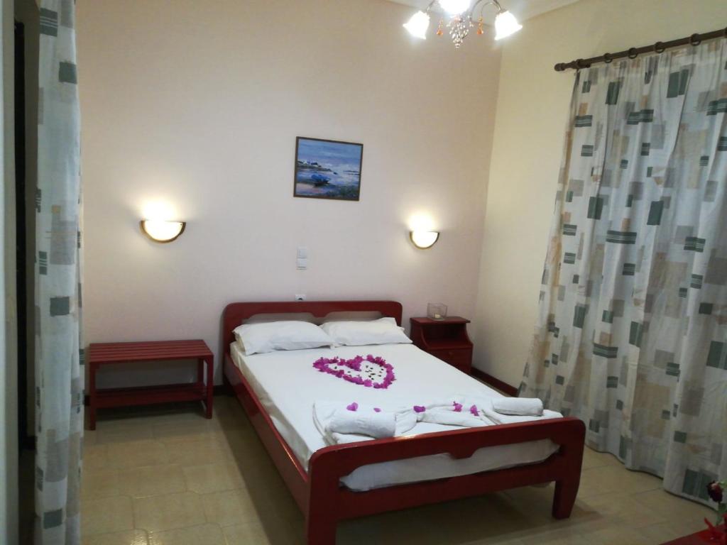 una camera da letto con un letto con lenzuola bianche e fiori rosa di Margarita rooms a Kalamákion