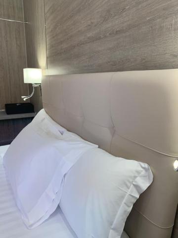 a white bed with white pillows and pillows at Hotel Tre Ville in Parma