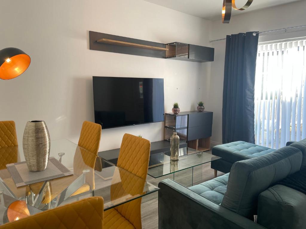 uma sala de estar com uma mesa de vidro e uma televisão em Modern & cozy 2 bed bungalow em Horden