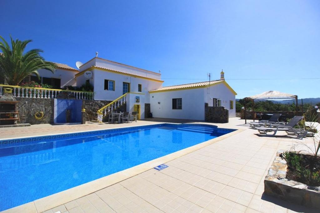 a villa with a swimming pool in front of a house at Casa Branca Holiday Resort in Salir