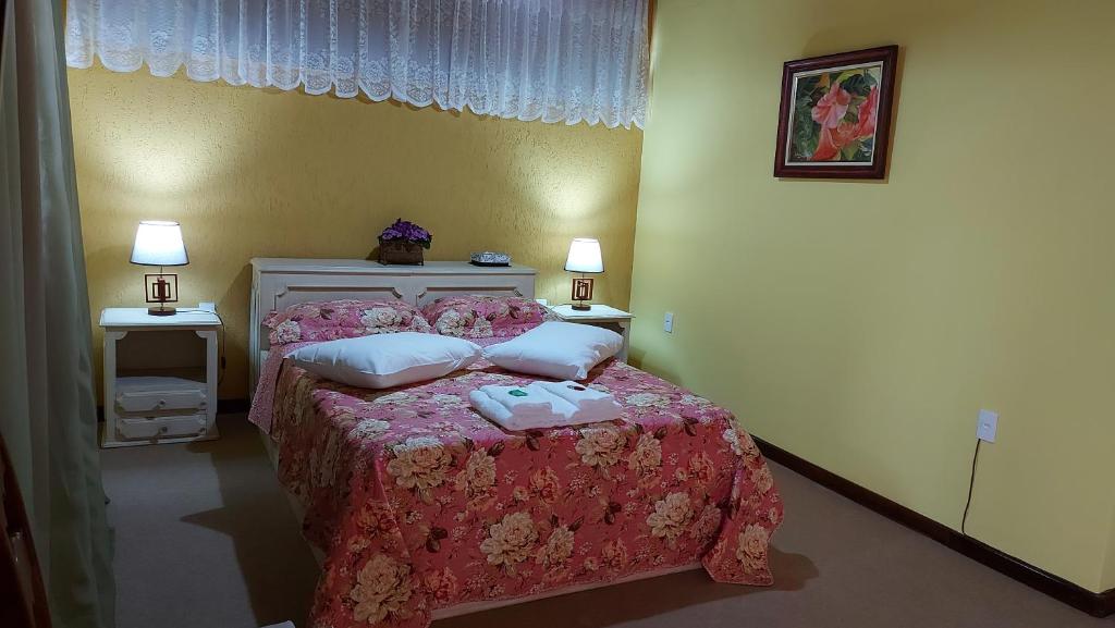a bedroom with a bed with a pink blanket and pillows at Suíte com vista da Serra in Teresópolis
