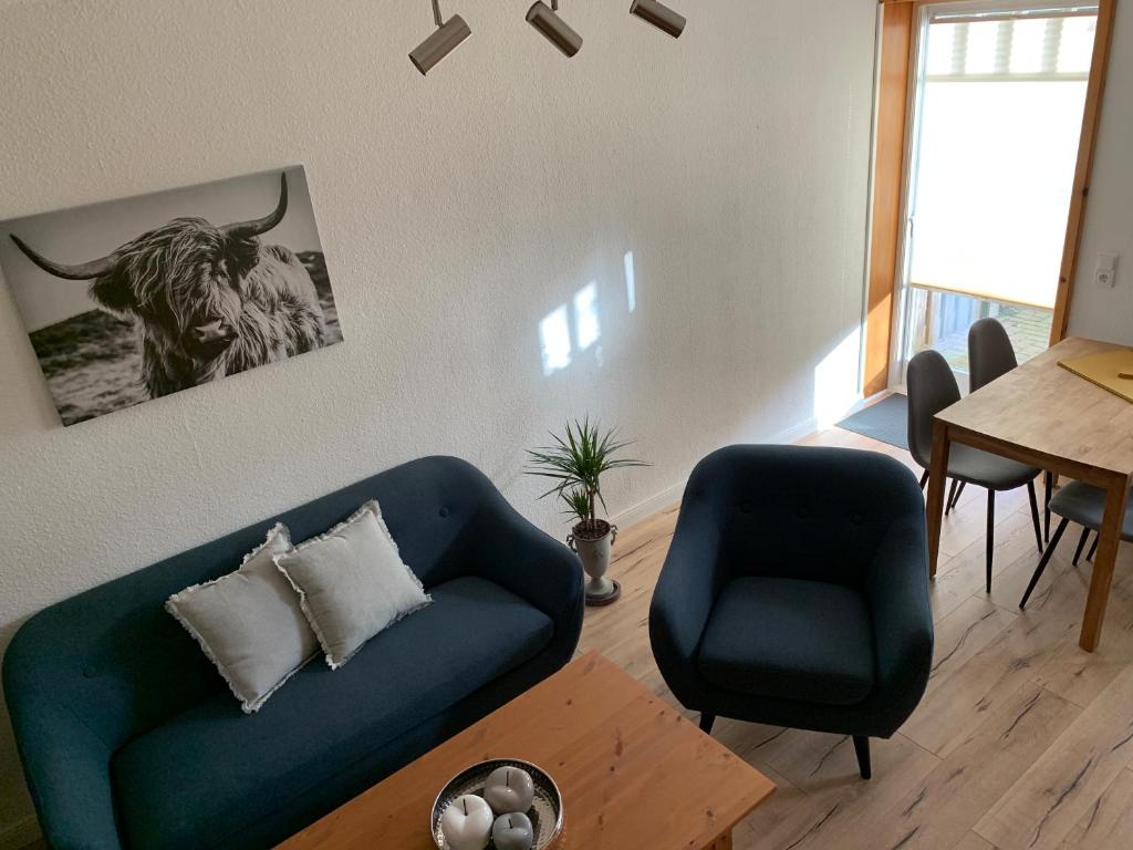 ein Wohnzimmer mit einer blauen Couch und einem Stier an der Wand in der Unterkunft Lüttje Koje in Breklum