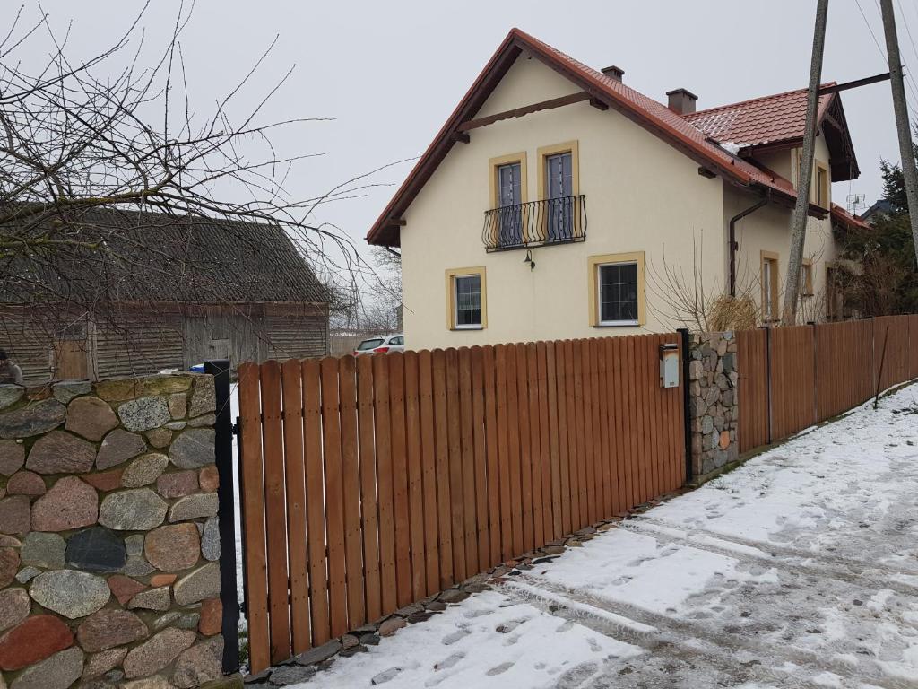 una valla de madera frente a una casa en Agroturystyka Wielkie Leźno en Wielkie Leżno