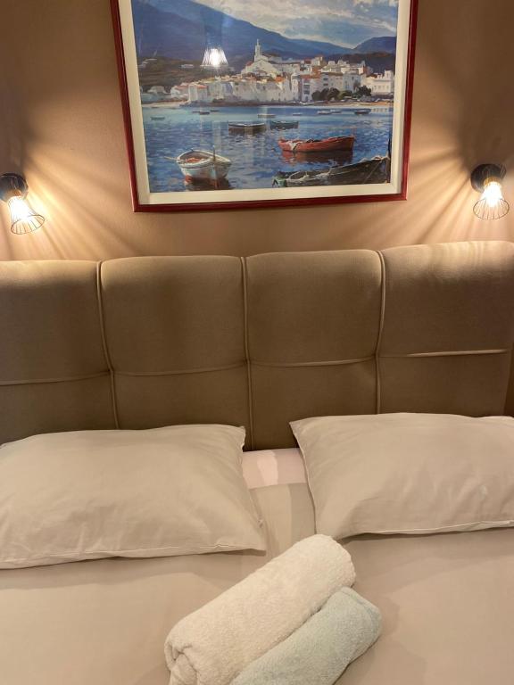 a bed with two pillows and a painting on the wall at Apartments Oliva in Poreč