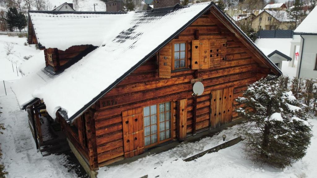eine Blockhütte mit Schnee auf dem Dach in der Unterkunft ChatauBrata in Krynica-Zdrój