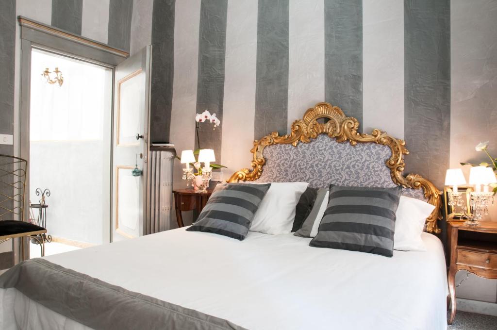 una camera da letto con un letto bianco con cuscini bianchi e neri di BIBI BOUTIQUE AREZZO Cartazucchero - Cioccolato ad Arezzo