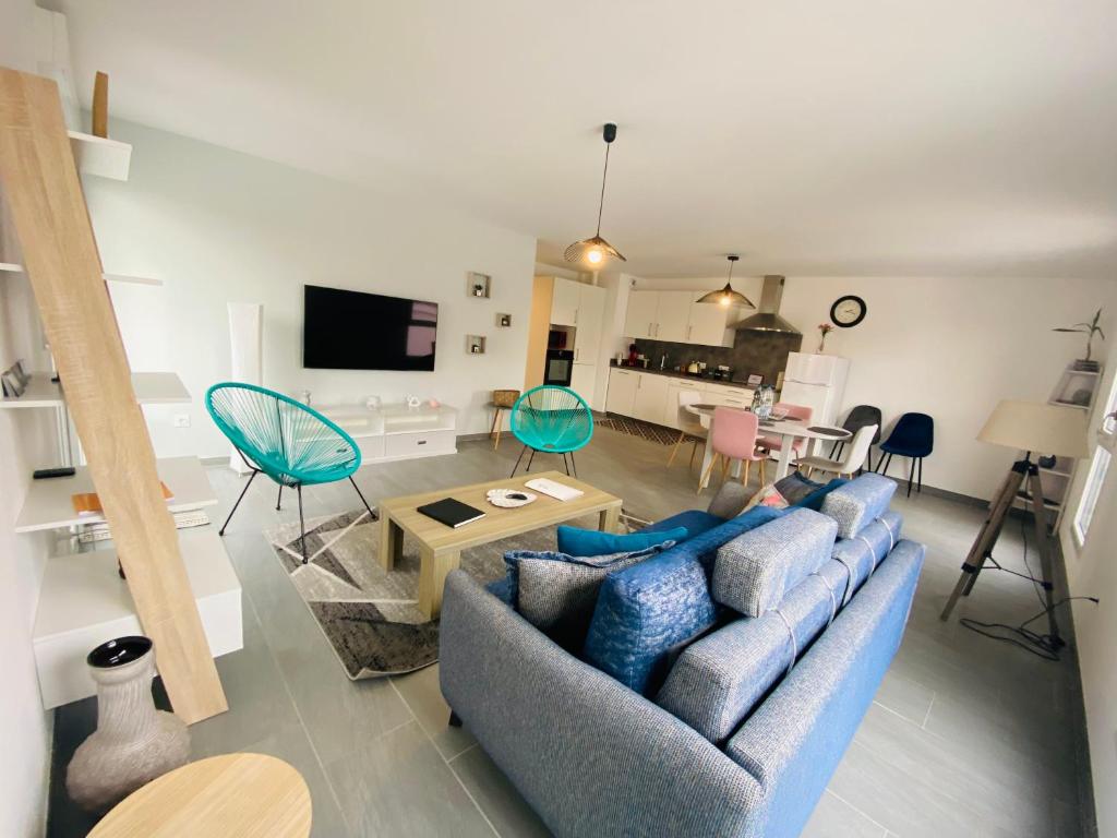 uma sala de estar com um sofá azul e uma mesa em Appartement Orchidées proche centre Ville em Colmar