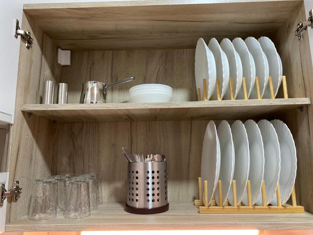 a wooden shelf with plates and utensils on it at Lilyy in Leskovac