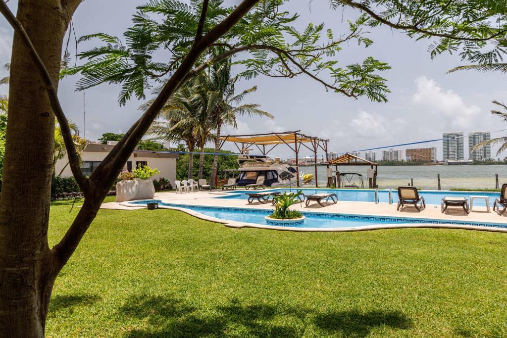 a swimming pool in a park with a tree at Villas La Marina in Cancún