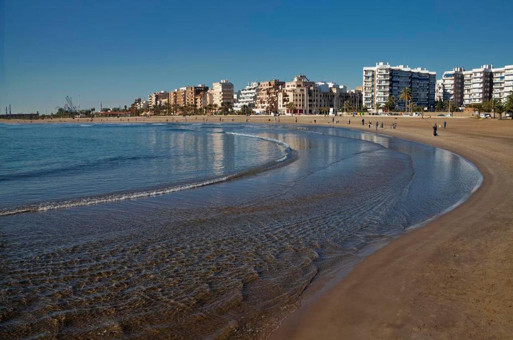 ein Strand mit Gebäuden und Menschen, die auf dem Sand laufen in der Unterkunft UIM Mediterraneo Diagonal 16 Wfi in Puerto de Sagunto