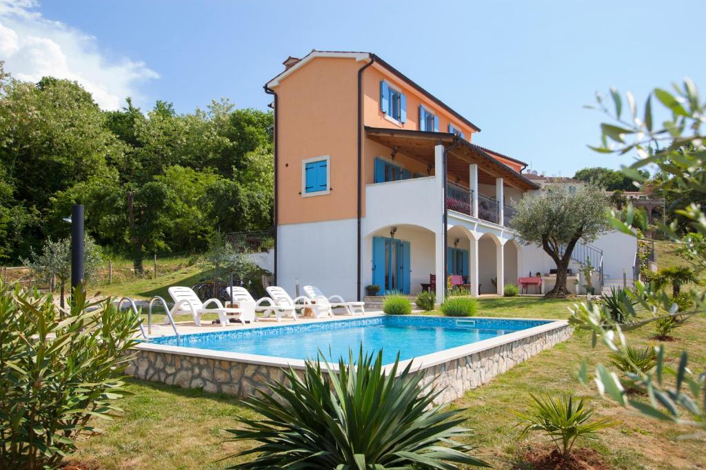 a villa with a swimming pool in front of a house at Relax in nature villa Mugeba Club in Poreč
