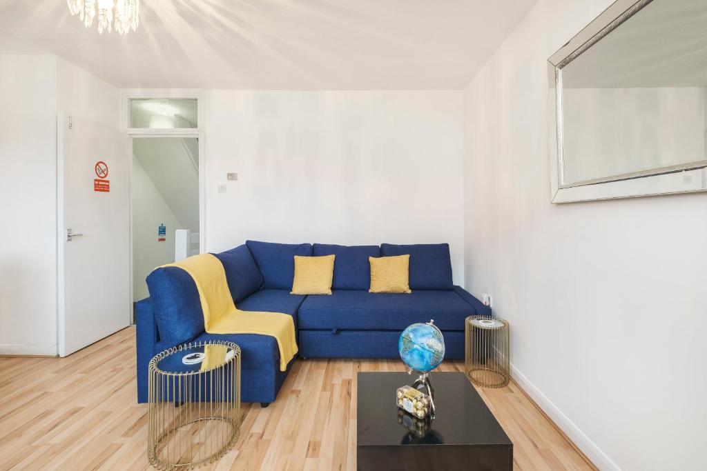 a living room with a blue couch and a table at Spacious, 3 bedroom house with parking Near Excel in London