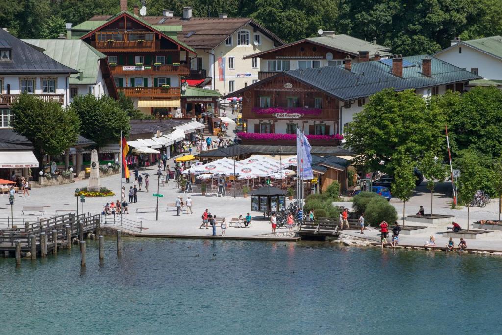 un grupo de personas caminando en un muelle junto a un cuerpo de agua en Hotel Königssee, en Schönau am Königssee