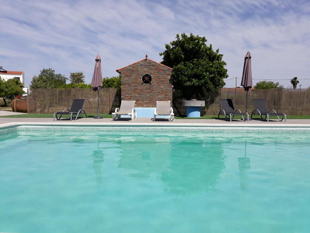 a swimming pool with two lawn chairs and umbrellas at Terras de Monsaraz in Reguengos de Monsaraz