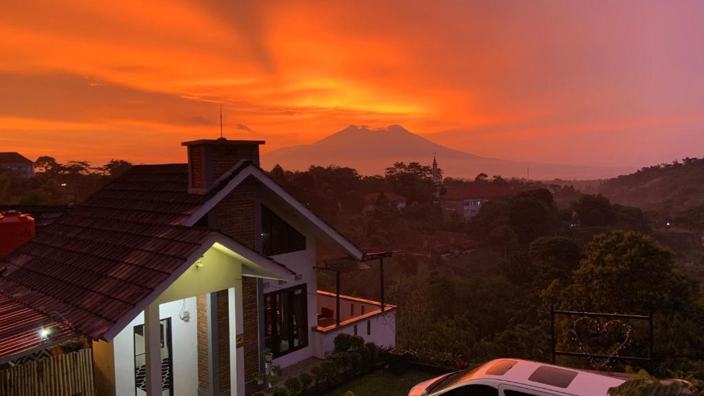 a house with a mountain in the background at sunset at Villa Kay Kay Mountain in Bogor
