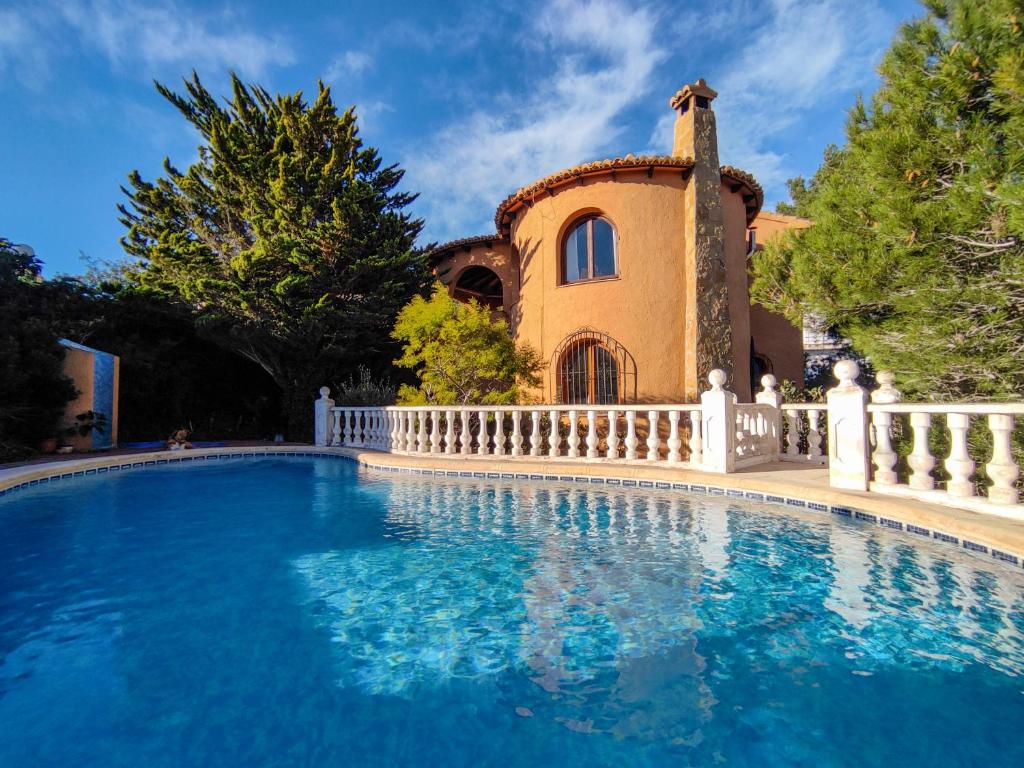 una piscina frente a una casa con una valla blanca en villa Anastasia, en Cumbre del Sol