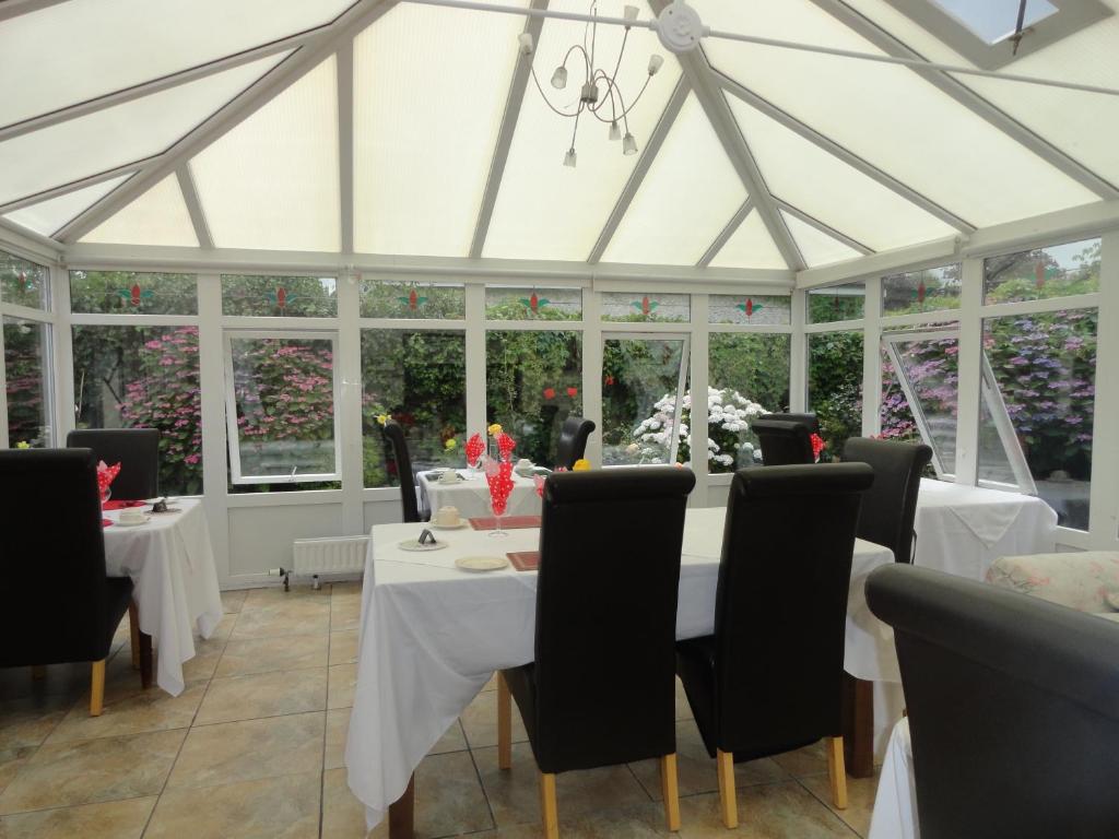 uma sala de jantar com mesas e cadeiras brancas e janelas em Orley House B&B em Drogheda