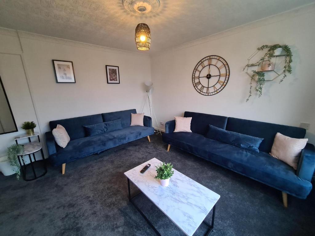 una sala de estar con 2 sofás azules y una mesa. en 6 bed, sleeps 8, 1 Mile from New Cross Hospital, 10 mins from M6 Jct 10 & M54 Jct 1, en Fallings Park